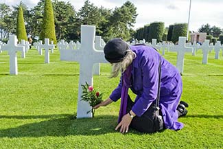 Cheryl Imboden lays a flower on a grave in the American Cemetery at 