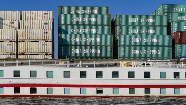 River cruise ship and shipping containers on the Elbe River in Hamburg, Germany.