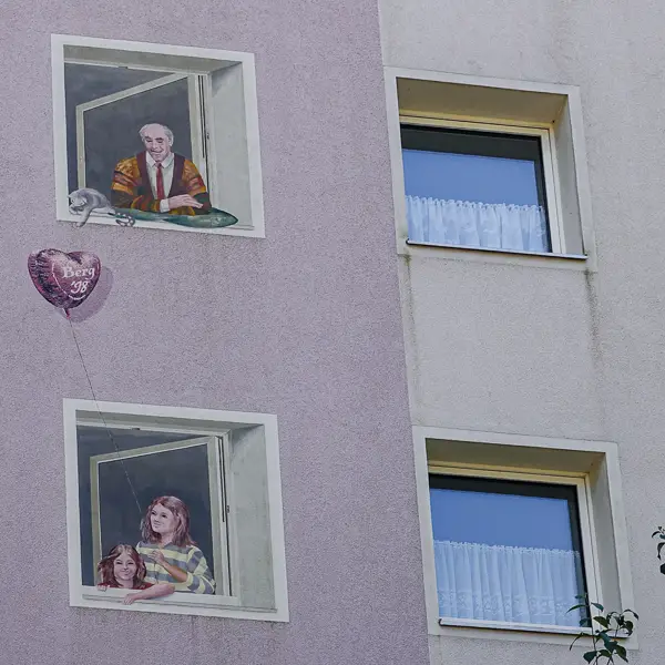 Murals of windows with people decorate an apartment building in Erlangen, Germany.