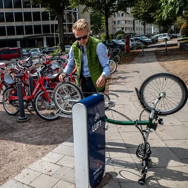A man adds free air to his bicycle's tires at a public 'Luft' station in Hamburg, Germany.y.