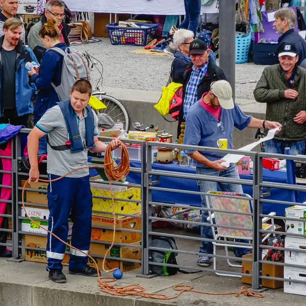 Shoppers at a weekend market in Koblenz, Germany share the Rhine riverfront with a dockworker.