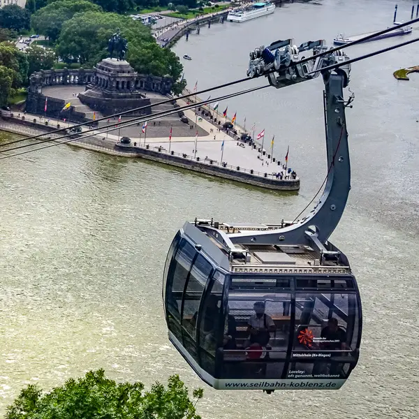 A gondola of the Seilbahn Koblenz rises above the Deutsches Eck, where the Rhine and Moselle rivers meet.
