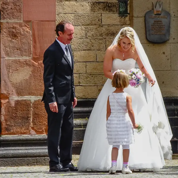 A bride and groom chat with a petite member of their wedding party in Koblenz, Germany.