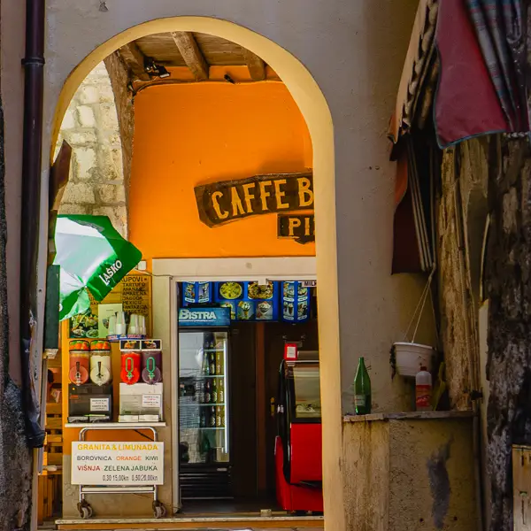 A coffee bar peeks through an arch in Rab, Croatia.