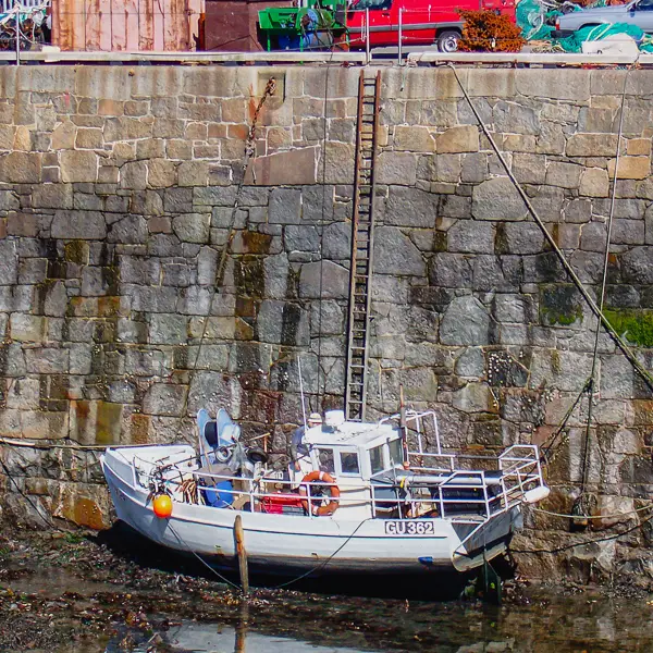 A boat rests on the harbor bottom in St. Peter Port, Guernsey at low tide. 