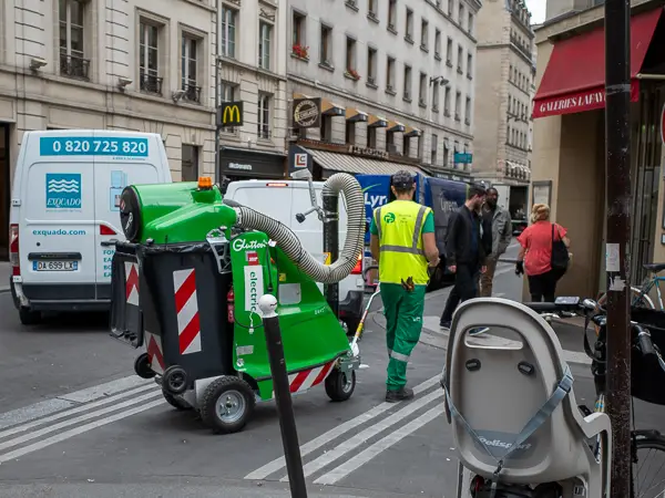 A streetsweeper maneuvers a mobile vacuum cleaner in Paris.