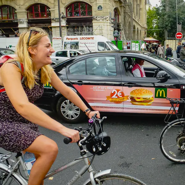 A bicyclist races a McDonald's car in central Paris.