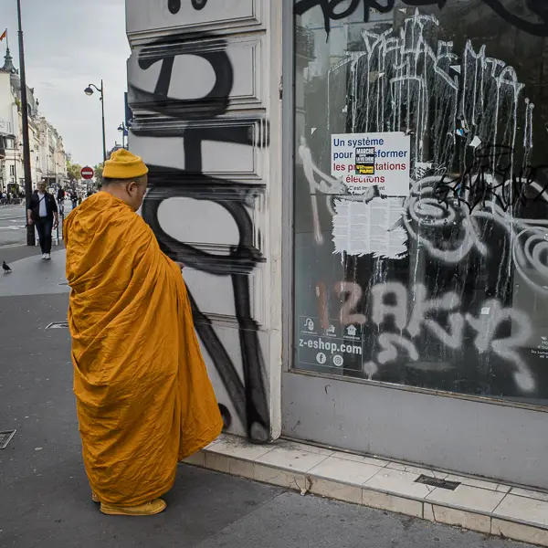 A monk contemplates an empty storefront in Paris.