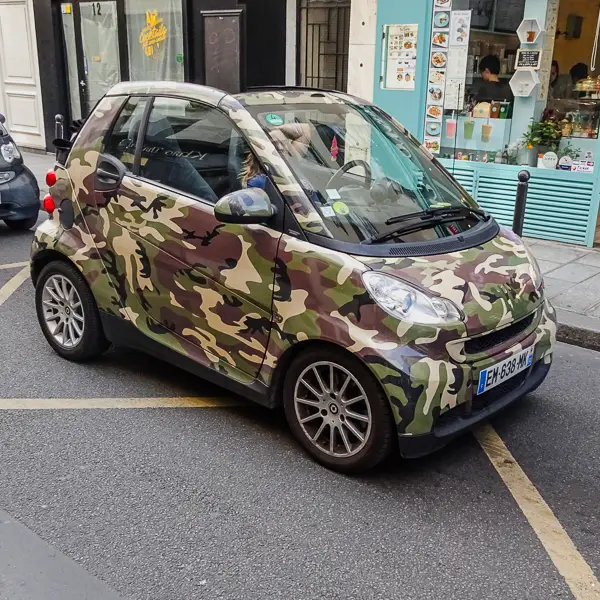A camouflaged car tries to blend in on a Paris street.