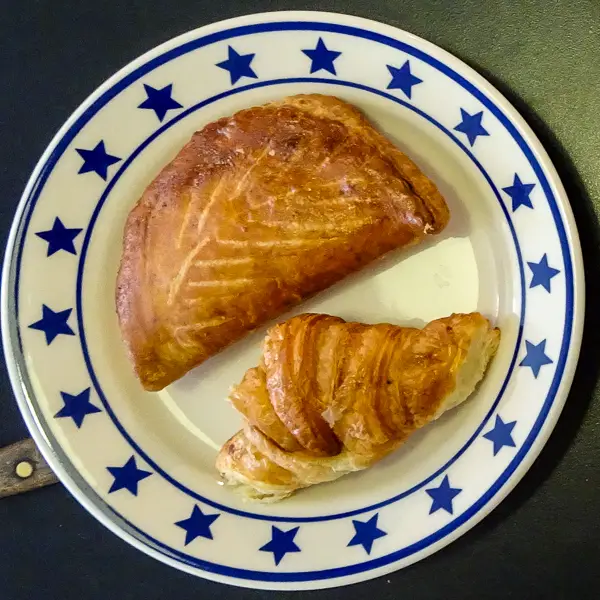 A chausson aux pommes and a croissant aux beurre pose for a Parisian pastry portrait.