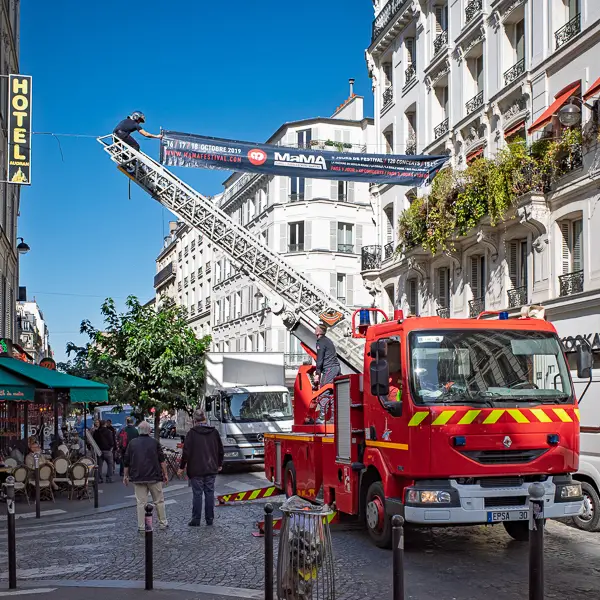 Firefighters hang a banner for a street festival in Montmartre.