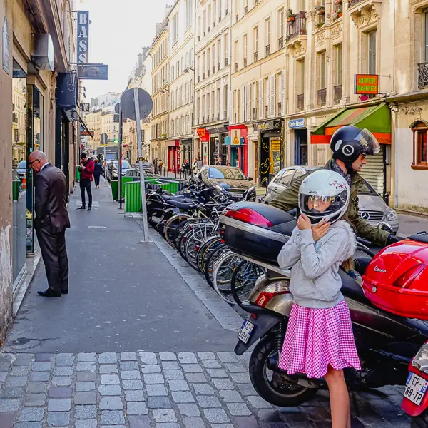  A girl unbuckles her helmet after a father-daughter motorscooter ride in Paris.
