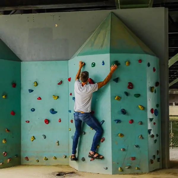 A man grips a climbing wall under a bridge on the Île des Cynes, or 'Isle of Swans,' in central Paris.