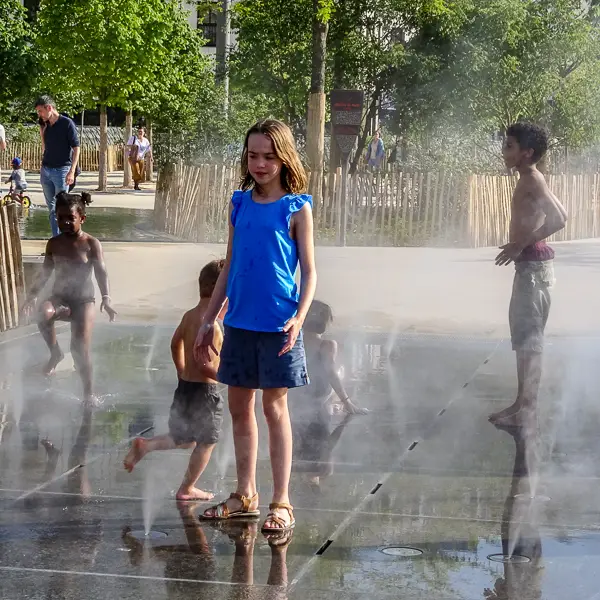Children cool off in a water sprayer at the Jardin Nelson Mandela in Les Halles.