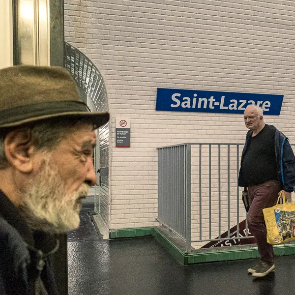Two men pass each other in a Paris 
		Metro station.
