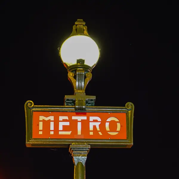 An illuminated M�tro sign beckons passengers after dark.