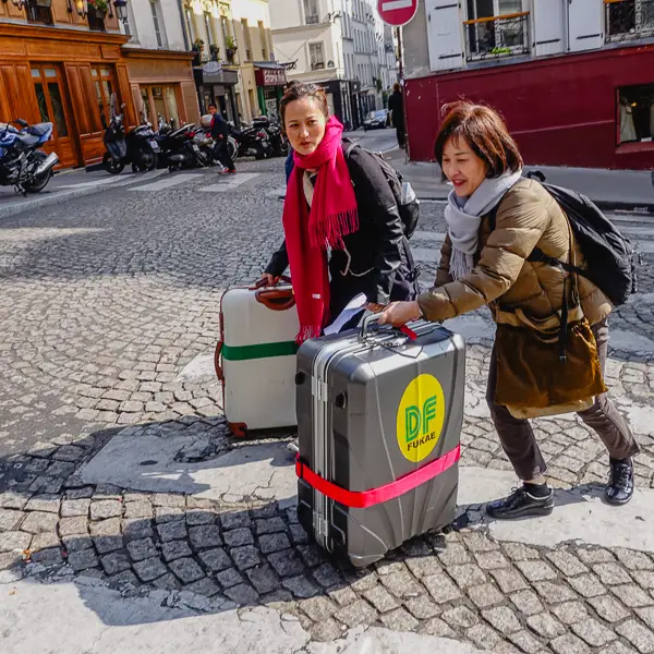 Women push suitcases through the streets of Montmartre by the Place Emile-Goudeau.
