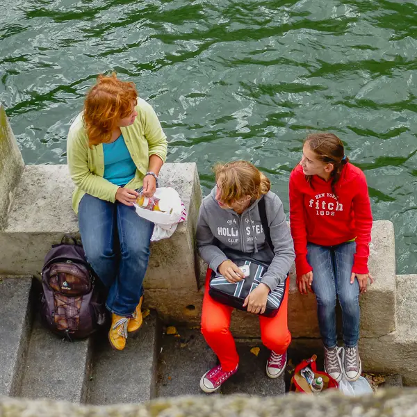  mother and her daughters find a place to sit along the Seine.