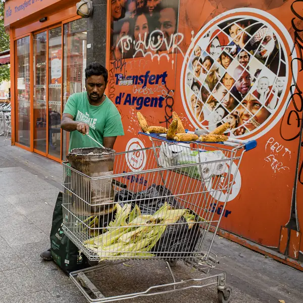 A street vendor in Saint-Denis, a suburb of Paris, sells roasted corn from a shopping cart.