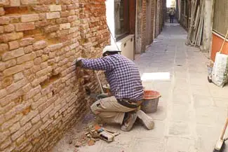 Bricklayer repairs Venice wall