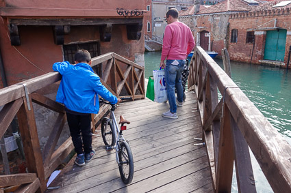 Boy with bicycle on Venice bridge