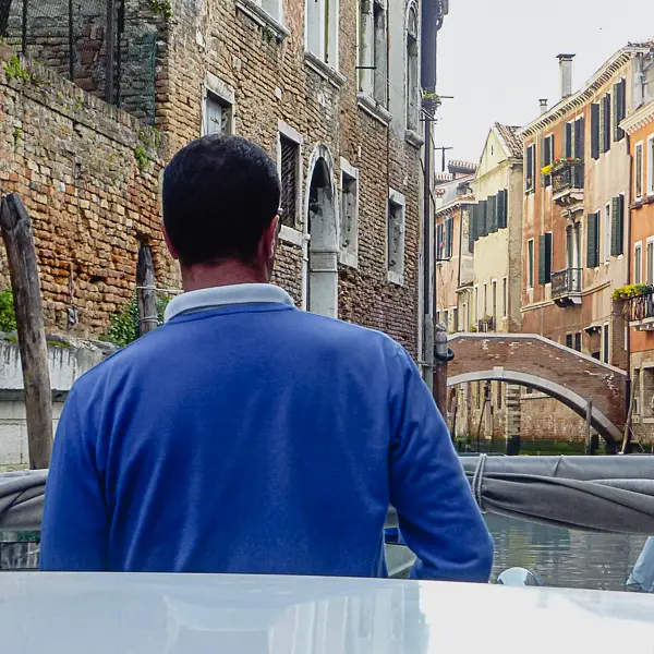 A water taxi's pilot navigates a side canal in Venice, Italy.