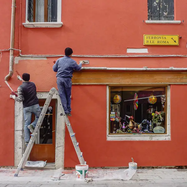 Workmen renovate the plaster façade of a building in Venice.
