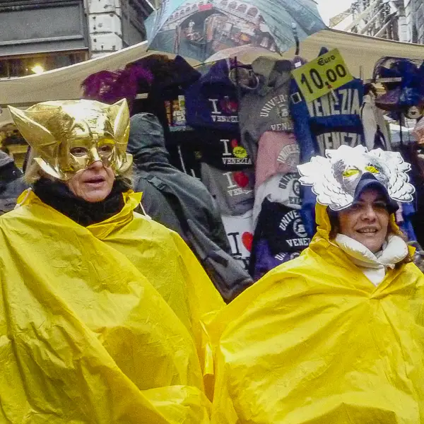 Carnival performers protect their costumes with plastic ponchos on a drizzly day in Venice.
