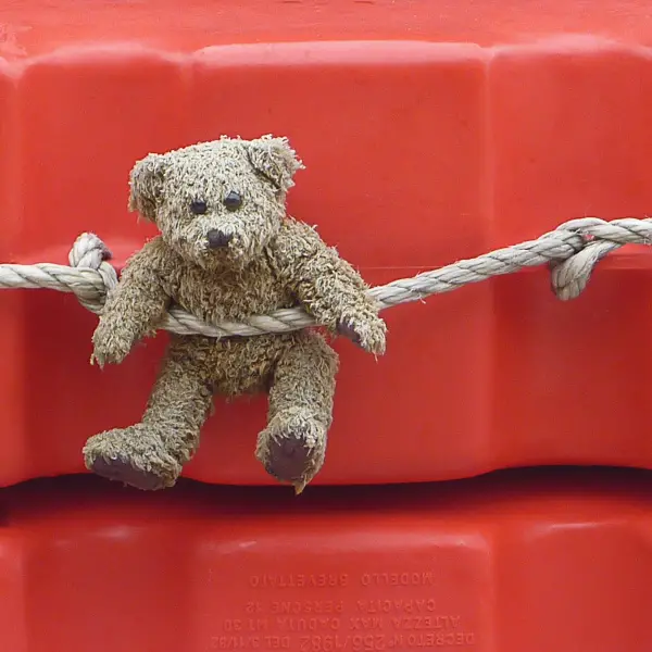 A teddy bear decorates a stack of life rafts on an Alilaguna water bus.