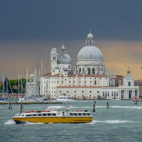 An Alilaguna boat cruises past Venice's Basilica di Madonna della Salute and the historic Customs House.