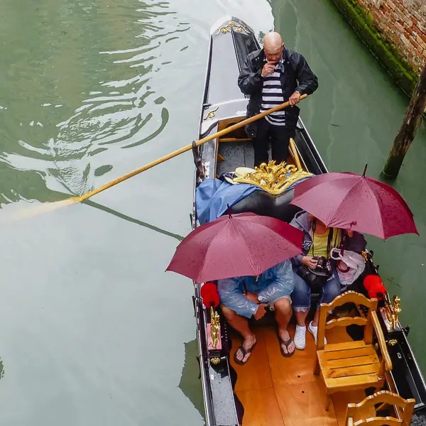 Gondola passengers use umbrellas on a rainy day in Venice.