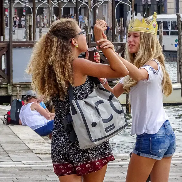 Two girls, one in a Burger King crown, enjoy sightseeing in Venice.