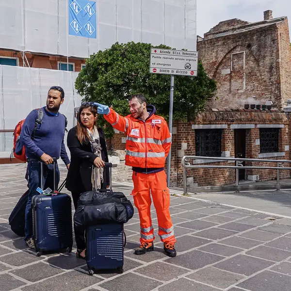 An ambulance attendant gives directions to visitors near Venice's Piazzale Roma.