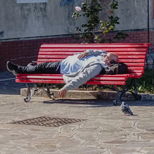 A man naps on a public bench in Venice, Italy.