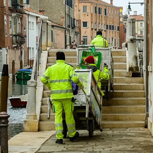 Spazzini (sanitation workers) haul their carts over a footbridge in Venice, Italy.