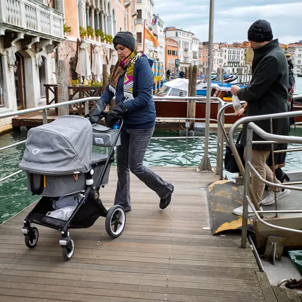 A mother pushes a stroller from an ACTV vaporetto stop on the Grand Canal in Venice.