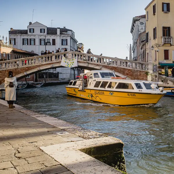 An Alilaguna 'Orange Line' airport boat passes under the Ponte delle Guglie in Venice, Italy.