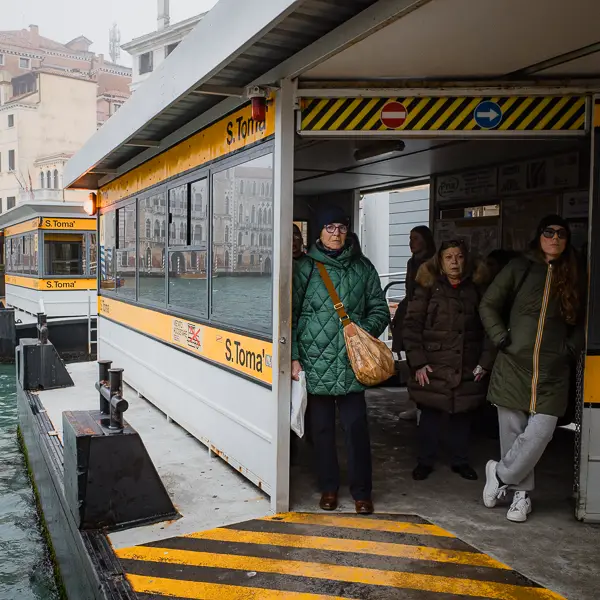 Passengers wait to board an arriving vaporetto at the San Toma stop on Venice's Grand Canal.