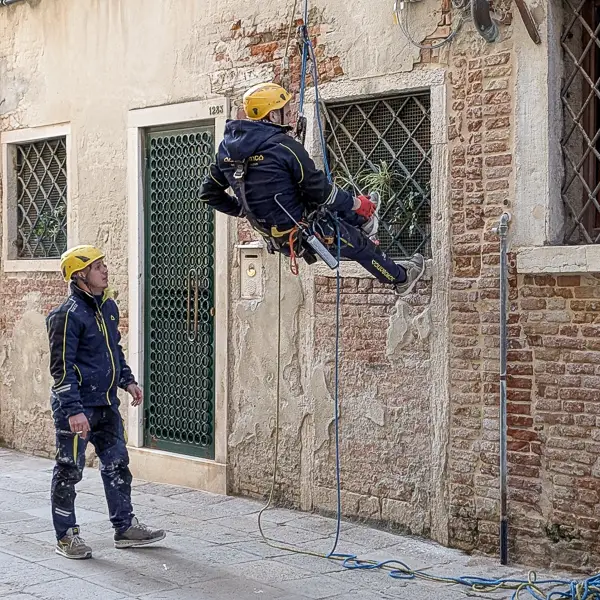 Climbers prepare to restore a building façade in Venice.
