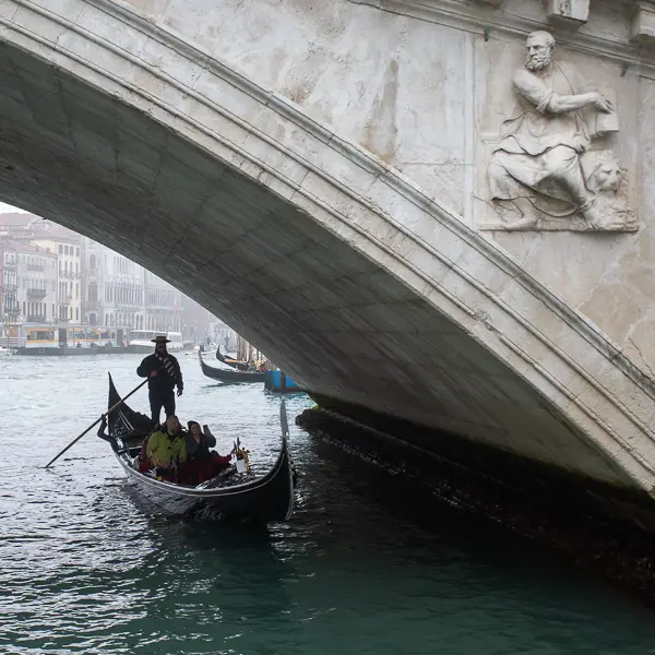 A gondolier rows his gondola under the Rialto Bridge in Venice, Italy.