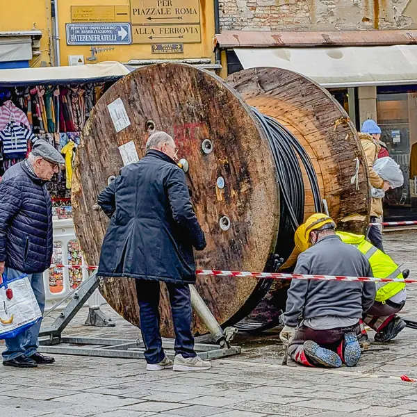 Sidewalk superintendents watch as telecom workers thread cable beneath paving stones in Venice's Cannaregio district.