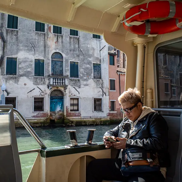 A transit passenger views his phone during an ACTV vaporetto ride on the Grand Canal.
