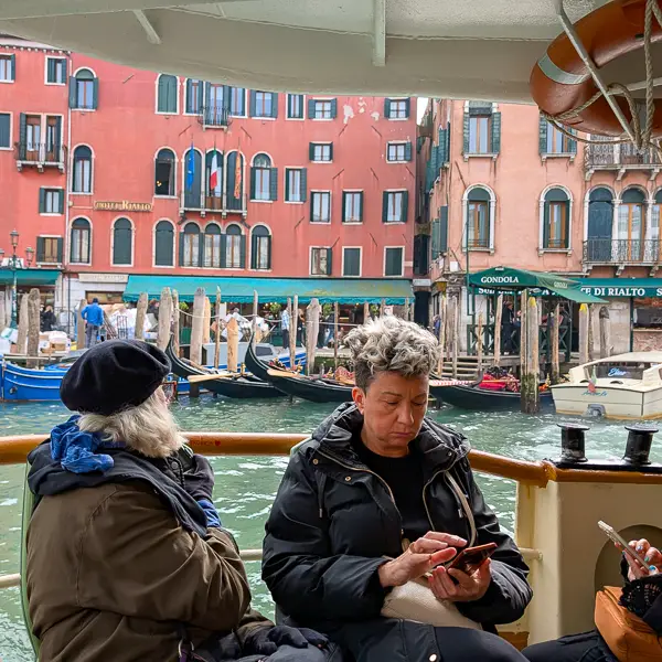 Passengers enjoy open-air seating in a public water bus on Venice's Grand Canal.