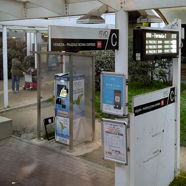 BELOW: At Venice Marco Polo Airport, the ATVO 'Venezia Express' bus stop is on the curb outside of the terminal. The stop has a ticket machine, a ticket validation machine, a printed timetable, an electronic departures sign, and information on using 'Scan & Go' to pay by smartphone. Look for the 'Fermata C' bus stop: