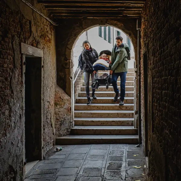  A mom and dad carry their baby's stroller over one of the 400+ footbridges in Venice, Italy.