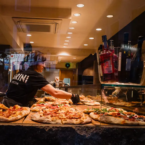 A woman cuts slices at a Farini pizzeria in Venice, Italy.