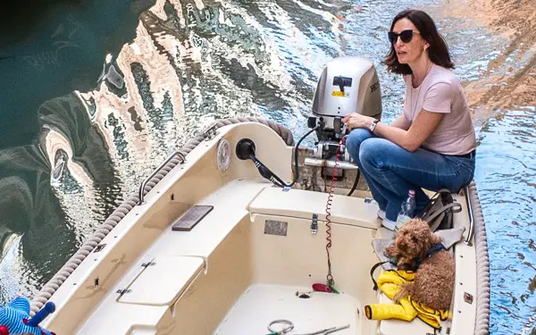 A woman and a dog share a boat in Venice, Italy.