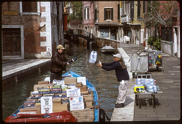 Men toss bottles from a boat in Venice, 1999